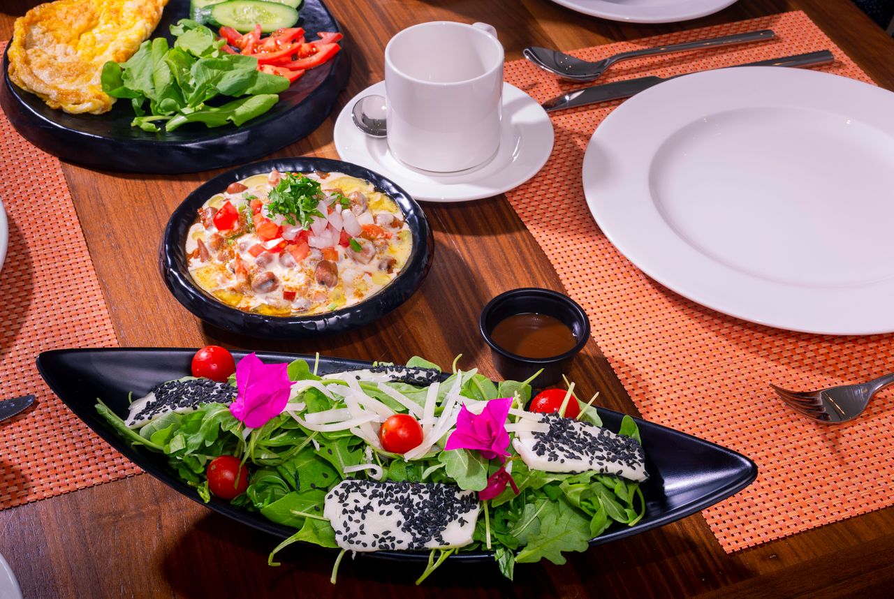 Colorful breakfast spread featuring fresh salad, omelet, and side dishes on a wooden table.
