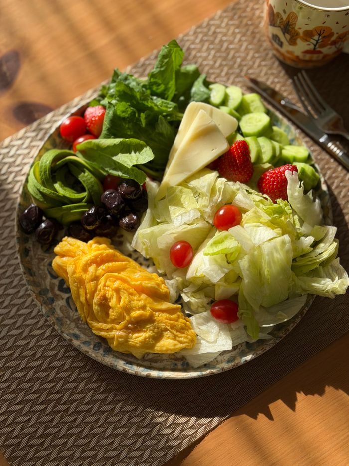 Colorful breakfast plate with omelet, fresh vegetables, and fruits.